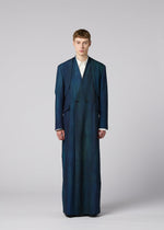 A person stands facing forward in an oversized, floor-length blue GRADATION WOOL coat from IM MEN over a white shirt, against a plain gray background—part of the Autumn Winter 2026/27 collection.