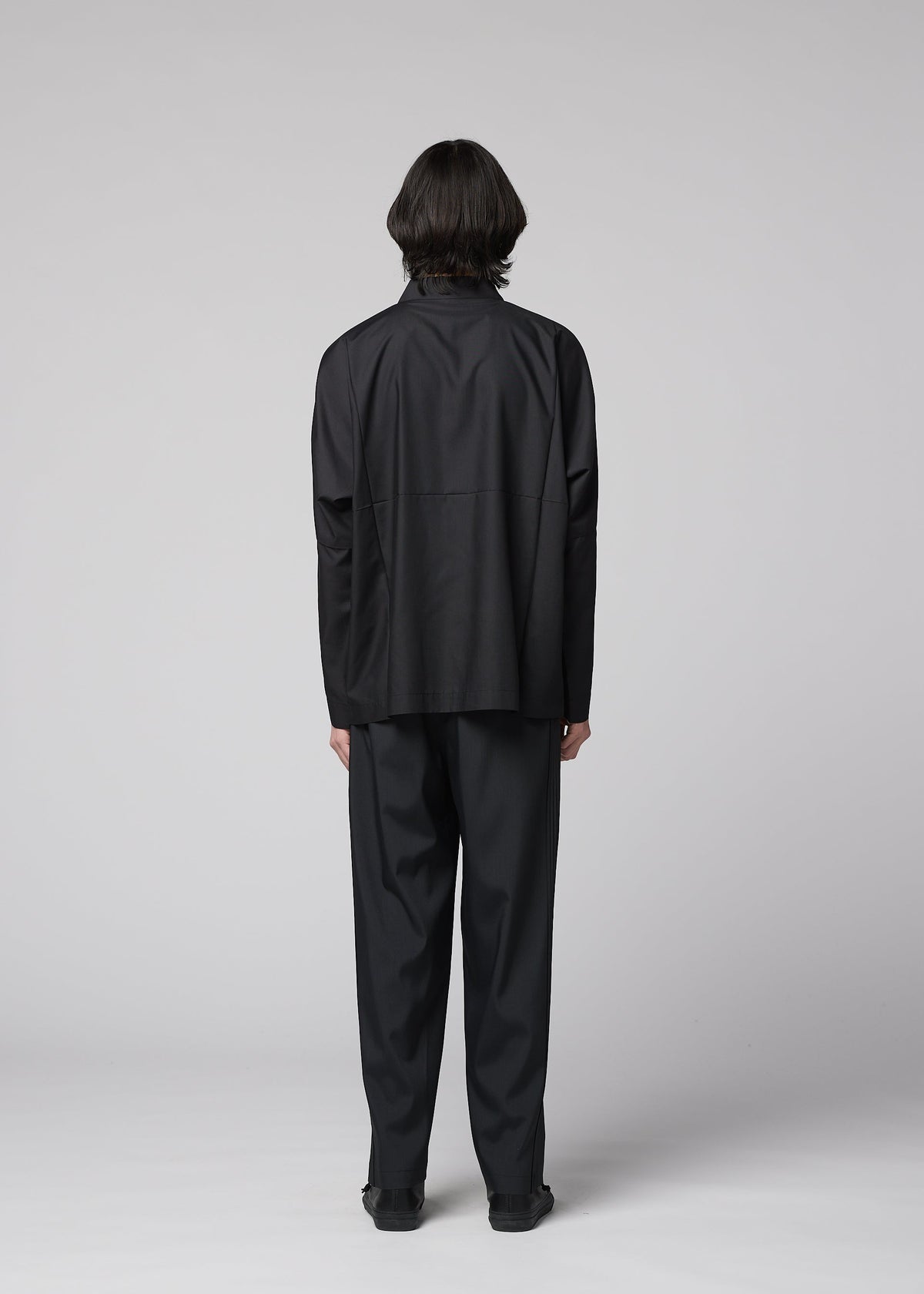 A person with medium-length dark hair faces away, wearing the IM MEN COMPACT SHIRT BLACK and matching black pants, set against a plain light gray background. view 10 of 11