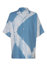 The ITAJIME SHIRT by IM MEN is a short-sleeve button-up featuring a light blue and white abstract pattern reminiscent of shadows or cloud shapes, inspired by the geometric designs characteristic of traditional Itajime Shibori dyeing, shown against a white background. - LIGHT BLUE （no.70）