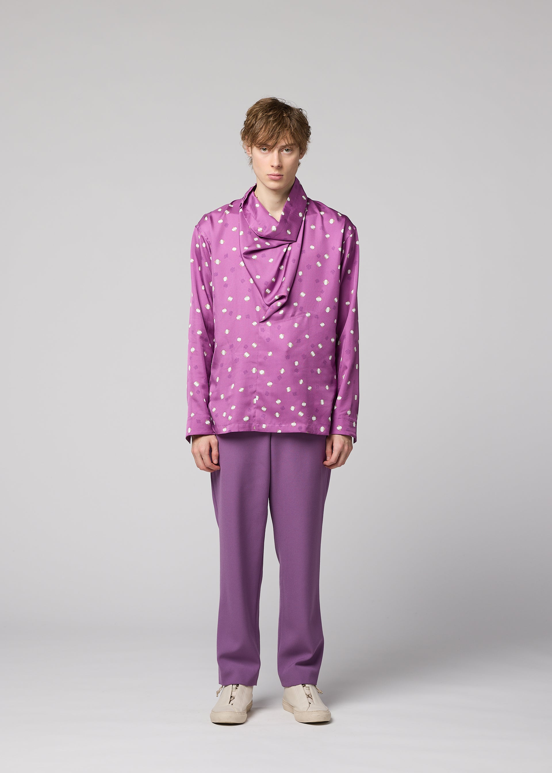 Zoomed view A person stands against a plain background, wearing the IM MEN MERRY SATIN SHIRT in purple with white polka dots, paired with matching purple pants and white shoes. Their expression is neutral and their posture relaxed.