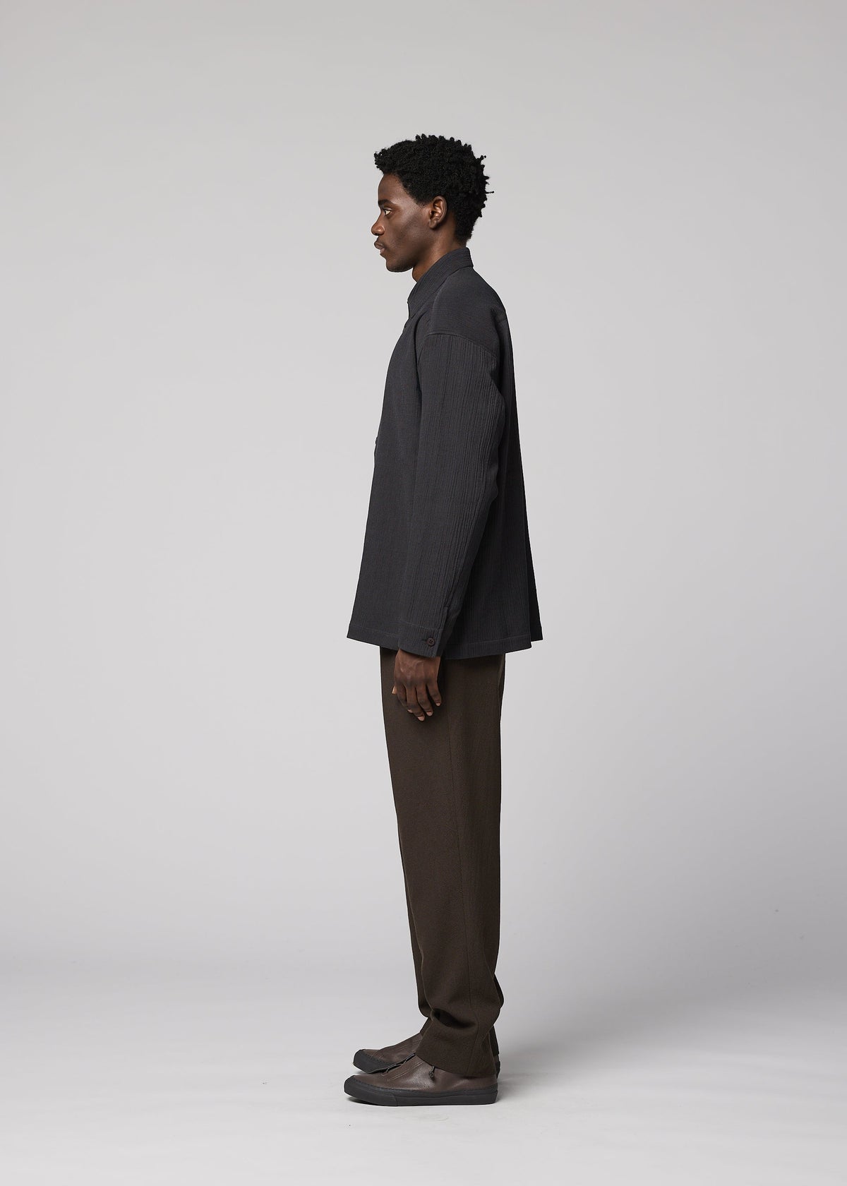 A man in profile stands against a plain light gray background, wearing the IM MEN DOUBLE WEAVE CREPE jacket, brown creased-texture pants, and dark shoes. view 6 of 8