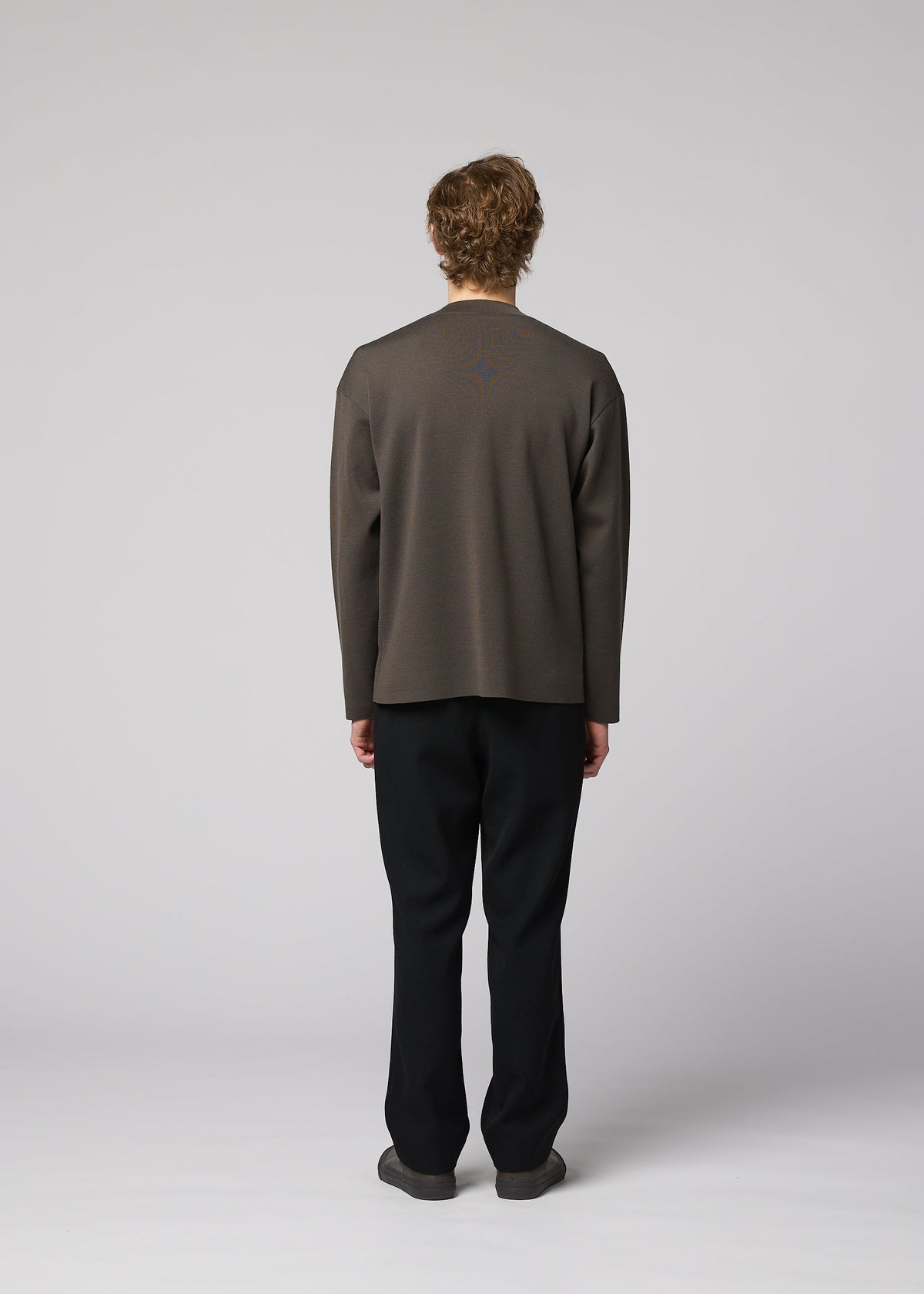 A person stands facing away from the camera, wearing IM MEN’s MONO-MILANO loose dark gray pullover and black pants against a plain light gray background. The wrinkle-resistant fabric of the MONO-MILANO ensures a polished look all day long. view 6 of 6