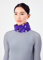 A woman with dark hair tied back wears a light gray textured top and the TIME DOTS PLEATS STOLE by me ISSEY MIYAKE, featuring purple pleats with white and black patterns, wrapped around her neck against a plain white background.