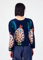 A person with straight, dark, chin-length hair is seen from behind, wearing the me ISSEY MIYAKE DAWN long-sleeved stretchy top with a colorful chicken and polka dot pattern, paired with dark blue pants against a plain white background.