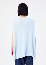 A person with straight, chin-length dark hair stands with their back to the camera, wearing the CURVE KNIT STRETCH PLEATS top by me ISSEY MIYAKE in light blue and dark blue pants against a plain white background.