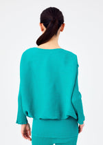 A woman with dark hair tied back is shown from behind, wearing the me ISSEY MIYAKE BALLOON SEE-THROUGH CREPE set in turquoise against a plain light background.
