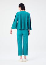A person with dark hair stands facing away against a white background, wearing the me ISSEY MIYAKE SWING PLEATS teal pleated knit long-sleeve top and matching pants, paired with white slip-on shoes.
