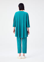 A person with straight, dark hair faces away, wearing the teal SWING PLEATS top and matching pants by me ISSEY MIYAKE, paired with white slip-on shoes against a plain white background.