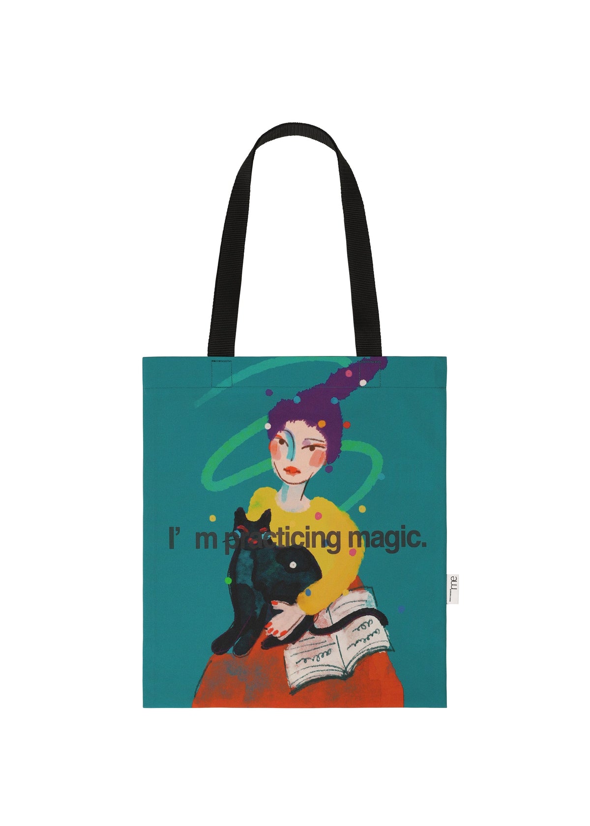The me ISSEY MIYAKE CAT BAG showcases a girl in a yellow shirt and purple hat holding a black cat, with an open book beside her, green swirls above, and the phrase "I'm practicing magic. view 4 of 4