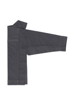 The FLAT DENIM jacket by me ISSEY MIYAKE, crafted from recycled polyester denim with tan stitching, is neatly arranged against a white background with one sleeve extended.