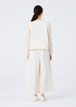 A woman with long dark hair in a low ponytail stands facing away, wearing the RIPPLE PLEATS set—hand-pleated white top and wide-legged pants with pockets—from me ISSEY MIYAKE, paired with white shoes against a plain white background.