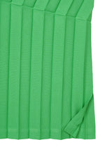 Close-up of the ZIG ZAG PLEATS skirt by me ISSEY MIYAKE, showing its green hand-pleated fabric with a slightly folded corner that highlights the zigzag silhouette and distinctive textured structure.