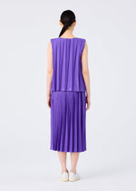A person with long dark hair in a low ponytail is seen from behind, wearing the CROSS PLEATS sleeveless purple top and hand-pleated skirt by me ISSEY MIYAKE, paired with white slip-on shoes against a plain white background.