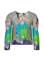 The CAT top by me ISSEY MIYAKE is a pleated long sleeve shirt with an artistic print of a person with green hair holding a green cat, set among abstract blue, green, and purple patterns.
