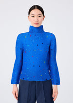 A woman with straight black hair in a low ponytail wears the TWINKLE STAR high-neck long-sleeve top from me ISSEY MIYAKE, featuring a colorful star print. She is facing forward against a plain white background.