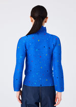 Someone with long, dark hair in a low ponytail is seen from behind, wearing the me ISSEY MIYAKE TWINKLE STAR high-neck long-sleeve top featuring a colorful star print, paired with dark pants.
