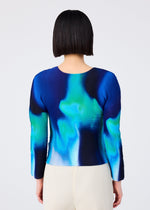 A person with a straight bob is shown from the back, wearing the me ISSEY MIYAKE AURORA round-neck long-sleeve top in blue-green aurora pattern, paired with light pleated pants against a plain background.