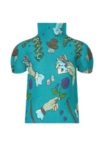 The MAGIC top by me ISSEY MIYAKE is a turquoise high-neck, short-sleeved piece with puffy sleeves, decorated with a magic marker print of hands holding cards, dice, hats, flowers, and green ribbons. - TURQUOISE-HUED (no.77)