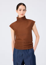A person with dark hair in a low ponytail wears the me ISSEY MIYAKE STRETCH PLEATS 4 brown high-neck top and blue wide-leg pants, standing against a plain white background with one hand in their pocket.