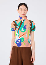 A woman with straight black hair wears the SURPRISE BOX short-sleeve top by me ISSEY MIYAKE, featuring a colorful jack-in-the-box pattern, and a brown pleated skirt. She stands facing forward against a plain light background.