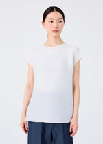 A woman with dark hair pulled back stands facing forward and looks to her right. She wears a white me ISSEY MIYAKE SQUARE STRETCH PLEATS top with French sleeves, paired with dark blue pants.