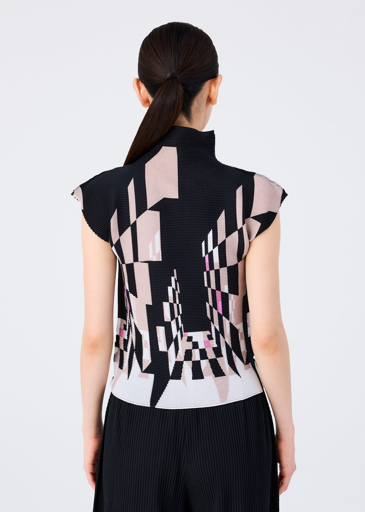 A person with long dark hair in a low ponytail is seen from the back, wearing the PERSPECTIVE high-neck top by me ISSEY MIYAKE, featuring French sleeves and a geometric black, beige, and pink optical pattern in STRETCH PLEATS. view 5 of 6