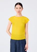 A woman with straight dark hair tied back wears a bright yellow STRETCH PLEATS 6 top from me ISSEY MIYAKE and high-waisted blue pants. She faces forward against a plain white background with a neutral expression.
