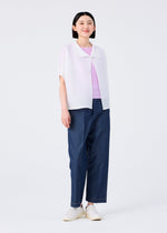 A person with straight dark hair wears a light purple top, a white short-sleeved cardigan, me ISSEY MIYAKE’s SQUARE STRETCH PLEATS blue wide-leg pants, and white slip-on shoes, standing against a plain white background and smiling slightly.