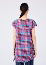 A person with long dark hair in a low ponytail is seen from the back, wearing the CHECK WHIPPED PLEATS SHIRT by me ISSEY MIYAKE in pink, purple, and blue over dark pants, set against a plain white background.