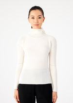 A woman with dark hair tied back wears the me ISSEY MIYAKE KNIT STRETCH PLEATS top in cream with black pants, standing against a white background and looking directly at the camera with a neutral expression.