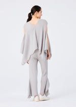A woman with a ponytail and white shoes stands against a white background, wearing me ISSEY MIYAKE’s FLAT SEE-THROUGH CREPE: a loose light gray top with uneven edges and matching wide-leg, sheer pants with flared, asymmetrical hems.