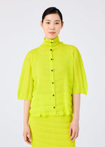 A woman with dark hair tied back models the me ISSEY MIYAKE RIPPLE SEE-THROUGH CREPE, a bright yellow-green pleated blouse with black buttons and matching skirt, against a plain white background.