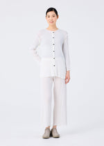 A person with short dark hair wears the me ISSEY MIYAKE SEE-THROUGH CREPE COLOR cardigan—loose-fitting, long-sleeved, garment-dyed with buttons—matched with wide-legged white pants and beige shoes against a plain white background.