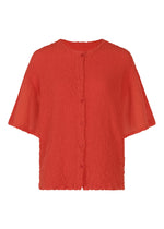 The SHEER CAULIFLOWER by me ISSEY MIYAKE is a bright red, textured short-sleeve button-up blouse with a round neckline and relaxed fit, inspired by the look of a cotton cardigan. - RED （no.24）