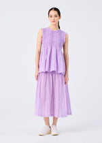 A woman poses against a plain white background in the SHIRT STRIPE CAULIFLOWER sleeveless top and pleated midi skirt by me ISSEY MIYAKE, her straight dark hair and white slip-on shoes completing the minimal, comfortable look.