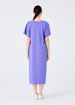 A person with long dark hair in a low ponytail faces away, wearing the me ISSEY MIYAKE FLAT JERSEY loose-fitting, short-sleeved, knee-length cotton-blend dress in purple, paired with white shoes against a plain white background.