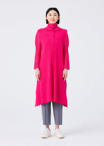 A woman faces forward against a white background, wearing the FLARE PLEATS long bright pink vest by me ISSEY MIYAKE over a matching turtleneck, paired with gray cropped pants and white slip-on shoes.