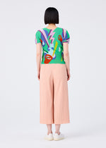 A person with short black hair, seen from behind, wears a vibrant top and light pink FINE KNIT PLEATS BOTTOM 2 pants by me ISSEY MIYAKE, plus white slip-on shoes, standing against a plain white background.