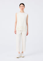 A woman with straight dark hair pulled back wears me ISSEY MIYAKE's FINE KNIT PLEATS BOTTOM 3 pants, a white sleeveless ribbed top with oval cutouts at the hem, and white slip-on shoes against a plain white background.