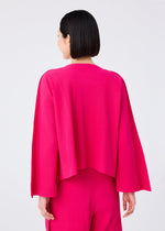 A person with short dark hair, seen from behind, wears the FLARE PLEATS set by me ISSEY MIYAKE—a bright pink, fine knit, long-sleeved top and matching flared pants—against a plain light background.
