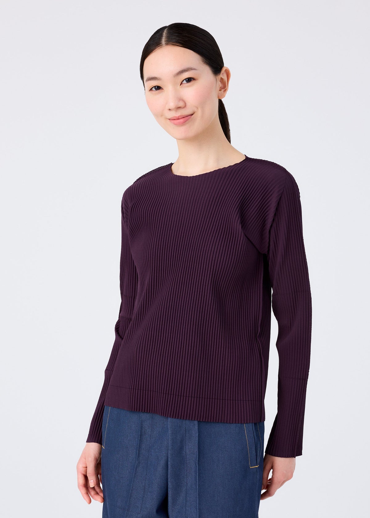 A woman wears the FINE KNIT PLEATS COLOR 1 long-sleeved top by me ISSEY MIYAKE in purple. view 6 of 8
