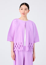 A woman wears the APERTURE PLEATS light purple pleated knit jacket with cutout hem details and matching fine knit pleated pants by me ISSEY MIYAKE, over a white top, standing against a plain background and gazing slightly to the side.