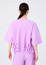 A person with long dark hair in a low ponytail is shown from the back, wearing the me ISSEY MIYAKE APERTURE PLEATS set—a loose-fitting, light purple pleated knit top with oval cut-outs near the hem and matching pants.