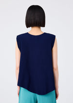 A person with straight, chin-length black hair is seen from behind wearing the me ISSEY MIYAKE AURORA PLEATS sleeveless top and teal pleated pants against a plain light background.