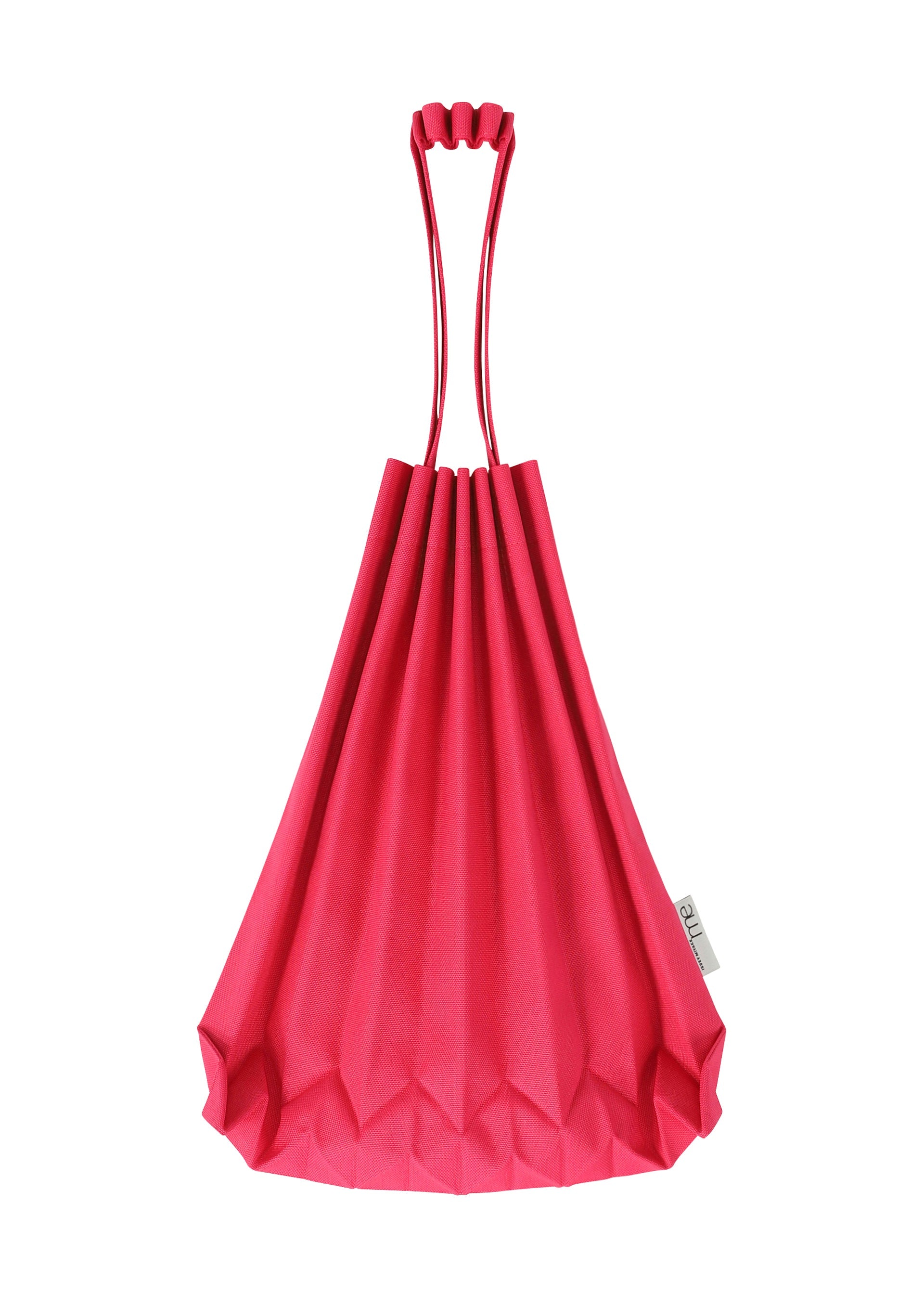 Zoomed view A TRUNK PLEATS BAG 12 by me ISSEY MIYAKE in bright pink, showcasing vivid color with long handles and a small white tag on the side, set against a white background.