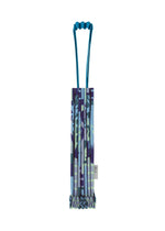 A folded, patterned BUILDING TRUNK PLEATS BAG by me ISSEY MIYAKE, featuring a unique handle and a multicolored blue, purple, and green camouflage-inspired design—perfect for urban adventures—stands upright on a white background. - BLUE-HUED （no.78）