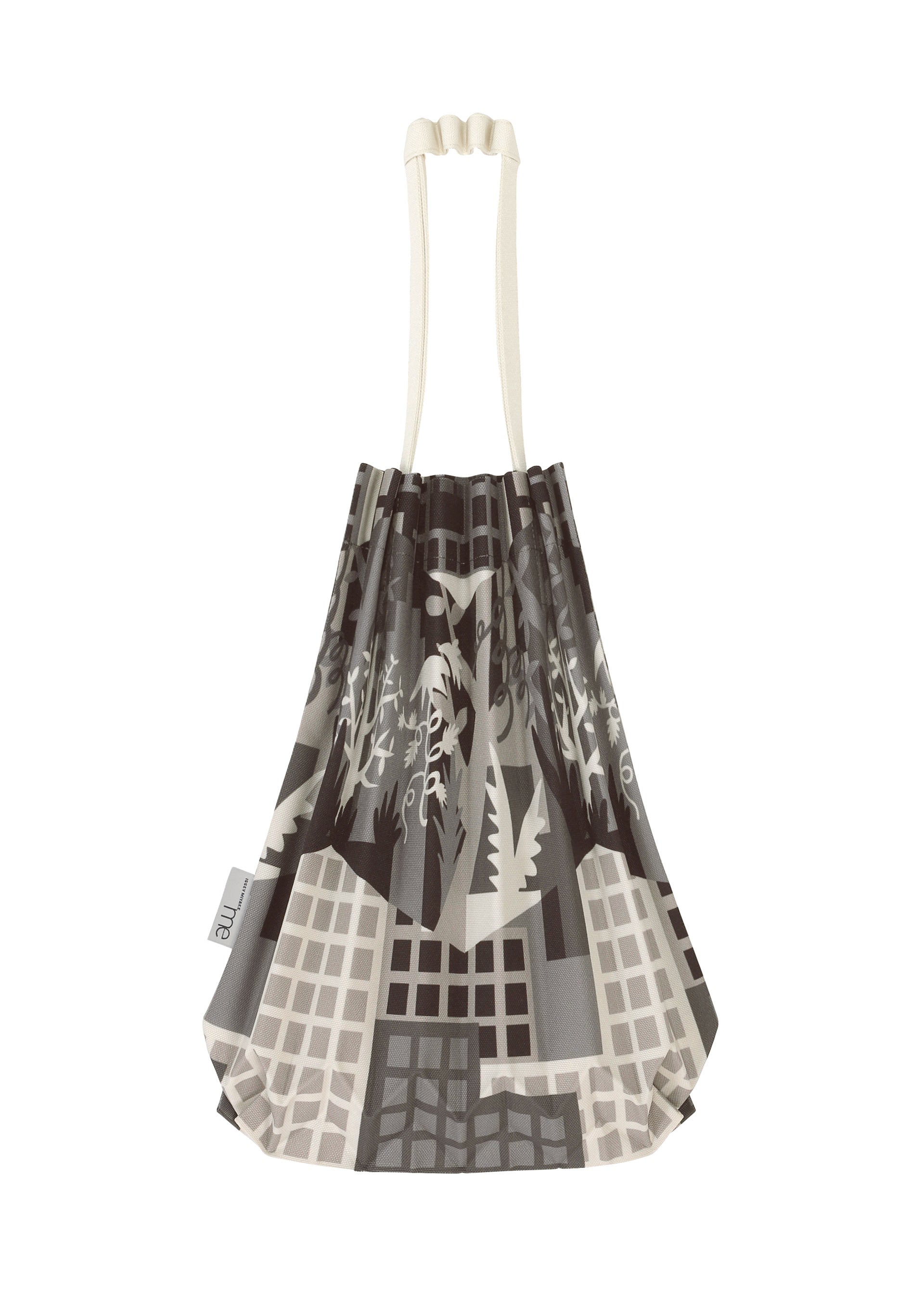 Zoomed view The BUILDING TRUNK PLEATS BAG by me ISSEY MIYAKE is a pleated mini tote featuring cream handles and an abstract grayscale cityscape design. The distinctive handle enhances its sophistication, while a small white tag accents one side.