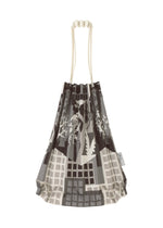 The BUILDING TRUNK PLEATS BAG by me ISSEY MIYAKE is a mini tote bag with distinct cream-colored handles, adorned with an abstract grayscale cityscape and plant motif inspired by urban farming. A small tag accents the side of the bag.