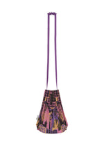 The BUILDING TRUNK PLEATS BAG by me ISSEY MIYAKE is a small shoulder bag featuring pleated detailing, a long purple strap, and a striking geometric pattern in shades of pink, purple, black, and gold.