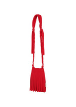 The LEAF PLEATS BAG by me ISSEY MIYAKE is a compact, vibrant red handbag featuring a pleated design and an elongated, knotted strap, styled in the manner of a chic jersey shoulder bag and showcased against a plain white background.